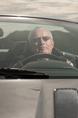 Senior good looking happy retired man driving his sports car.