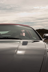 Obraz premium Senior good looking happy retired man driving his sports car.