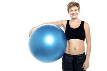 An attractive fit lady holding blue pilates ball