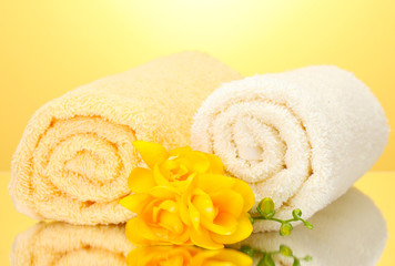 Obraz na płótnie Canvas kolorowe ręczniki i kwiaty na żółtym tle