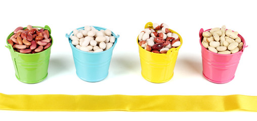 Different types of beans in colored buckets isolated on white