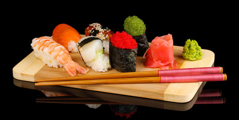 delicious sushi served on wooden board isolated on black
