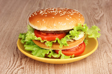 Big and tasty hamburger on plate on wooden table