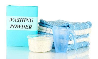 Box of washing powder with blue measuring cup and towels,