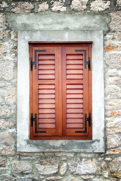 Brown wooden shutters in old stone house