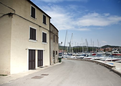 Fototapeta Old street of stone houses with bench by the sea