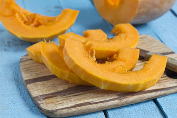 Fresh uncooked cutted pumpkin on board on wooden table
