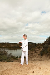 Senior spiritual man dressed in white.Exercising outdoors.