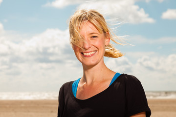 Happy pretty blonde woman on the beach. Enjoying outdoors. 