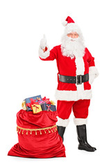 Santa Claus with a bag full of gifts giving a thumb up