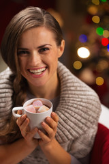 Smiling woman holding cup of hot chocolate with marshmallows