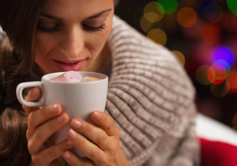 Young woman holding cup of hot chocolate with marshmallows