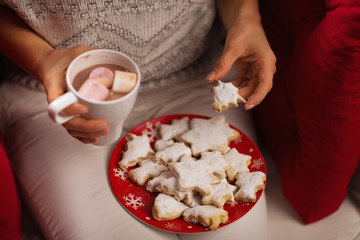 Closeup on woman eating Christmas cookie and drinking hot chocol