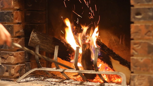Man burns wood in a stone fireplace at home in winter