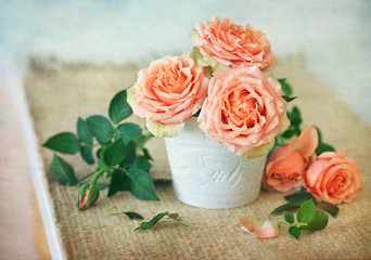 Beautiful fresh roses in a ceramic vase on a table.