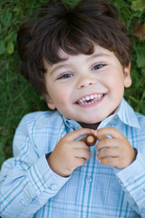 Beau petit gar&ccedil;on souriant allong&eacute; dans l'herbe