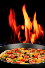 Delicious pizza with seafood on fire background