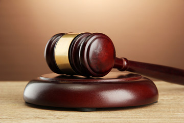 wooden gavel on wooden table, on brown background