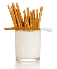 Tasty crispy sticks in glass with sour cream isolated on white