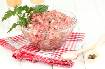 Bowl of raw ground meat with spices on wooden table