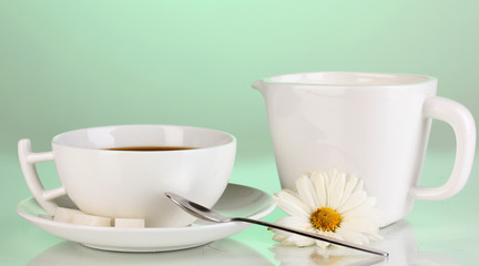 A cup of strong coffee and sweet cream on green background