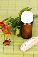 medicine bottle with tablets and flowers on bamboo mat