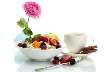 tasty oatmeal with berries and cup of tea, isolated on white