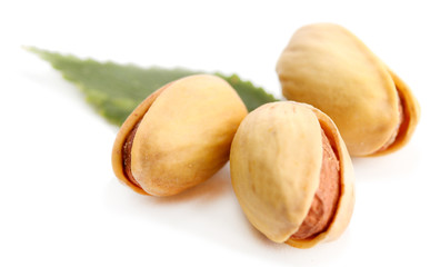 tasty pistachio nuts with leaves, isolated on white
