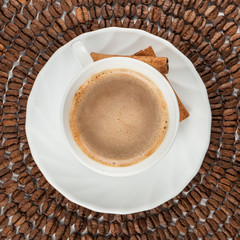 View from top on white cup of coffee with cinnamon sticks