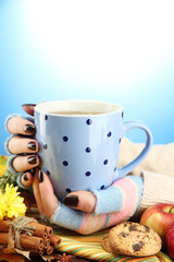 hands holding cup of hot drink and autumn leaves,