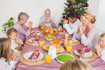 Family saying grace before christmas dinner