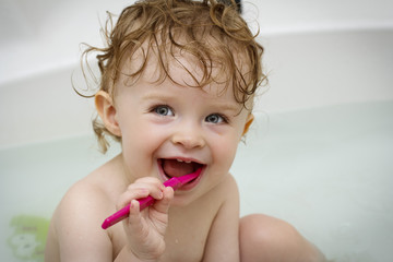 Little baby cleaning teeth in the bath
