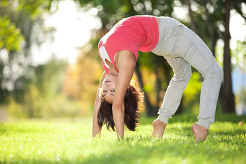 Pretty woman doing yoga exercises in the park