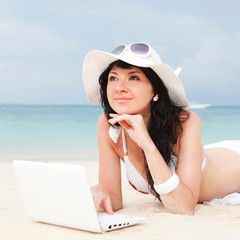 Cute woman with white laptop on the summer beach