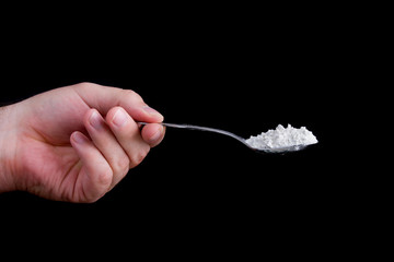 Hand holding a spoon full of a white powder