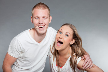 Young couple together in love against grey wall. Studio shot.