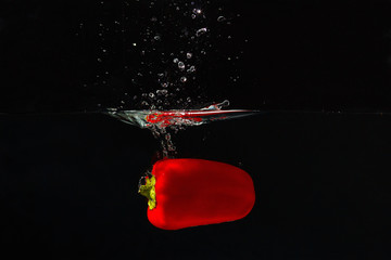 Red bellpepper falling into the water with a splash