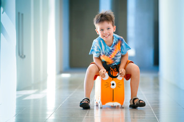 Cute happy boy with a suitcase at airport