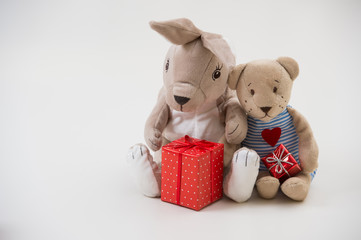 Retro style toy rabbit and bear sit hugging with gift boxes