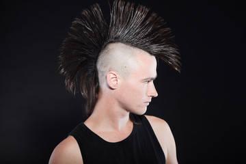 Punk man with mohawk haircut. Expressive face. Against black.