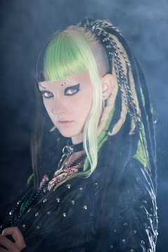 Cyber punk girl with green blond hair and red eyes against black