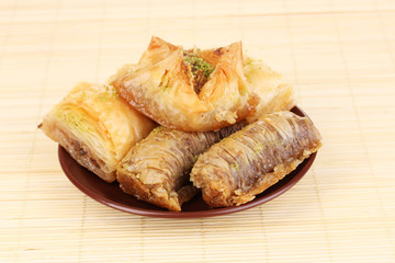 Sweet baklava on plate on bamboo mat