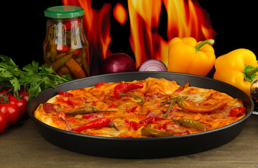 Tasty pepperoni pizza in pan with vegetables on flame