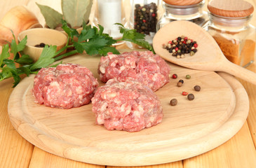 Raw meatballs with spices on wooden table