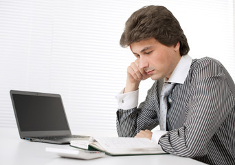 Portrait of a young businessman thinking while working on laptop