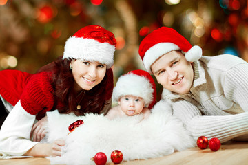 Fototapeta na wymiar Christmas family in red hats. Happy parents and baby