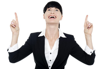 Excited businesswoman looking ad pointing upwards