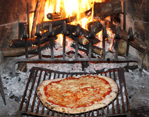 pizza margherita baked in to the fire of a fireplace in the tave