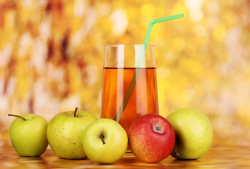 Useful apple juice with apples around on autumn background