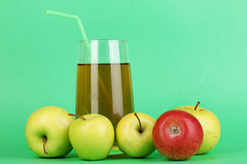 Useful apple juice with apples around on green background